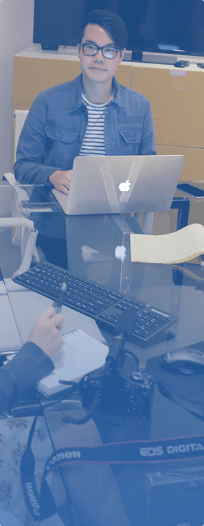 a young man working on a Mac laptop in a meeting